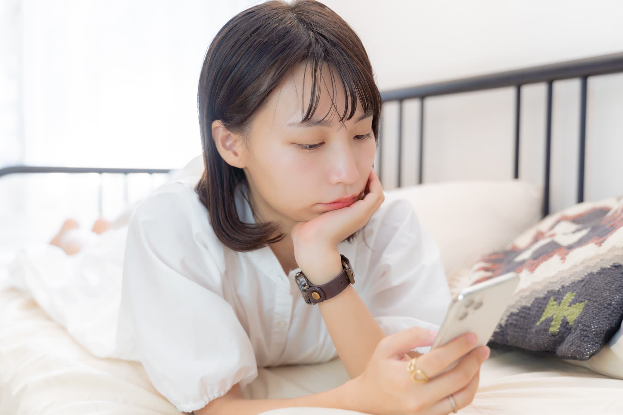 頬杖をついてスマホを見ている女性