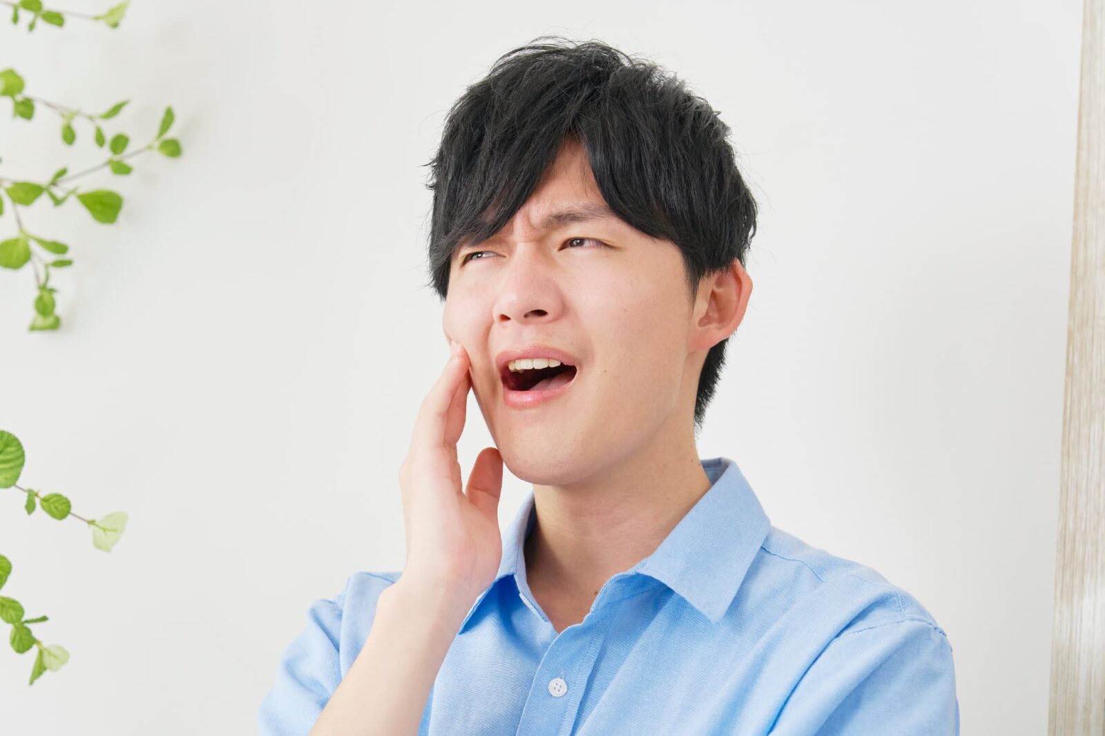 嚙み合わせの違和感や痛みを感じ頬を押さえる男性