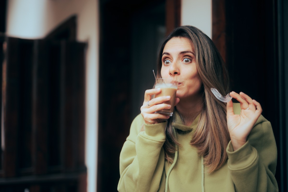 インビザラインのマウスピースを外してジュースを飲む女性